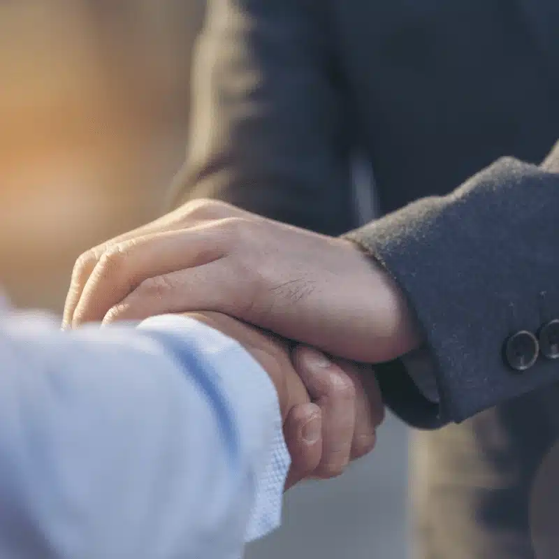 Gros plan sur une poignée de main entre deux personnes, symbolisant la confiance, la collaboration et la continuité d’un partenariat